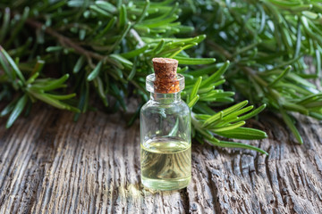 A bottle of rosemary essential oil with fresh rosemary twigs