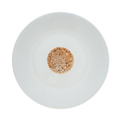 Top view of a small multigrain rice cake on a large plate isolated on a white background.