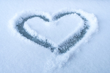 Heart shape drawn in a white snow.