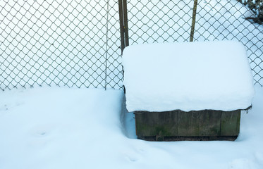 Doghouse in winter with a snowdrift on top, side view