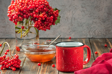 Still life berries of a viburnum in a glass and mug of hot tea and honey