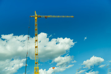 Obraz premium a construction tower crane, against a blue sky with white clouds
