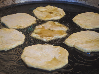 Romanian traditional Placinta are fried in a large frying pan.