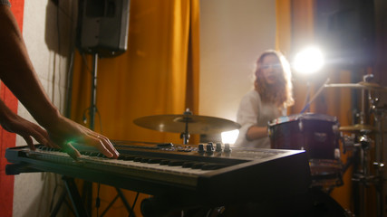 Repetition. Girl drummer and a guy on keyboards. Hands in focus