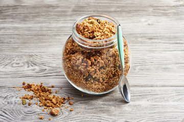 Homemade granola in a glass jar on a wooden table