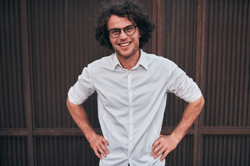 Outdoor shot of smilimg handsome young businessman with glasses posing outdoors. Male student...
