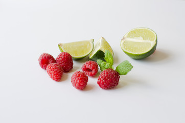 The composition of ripe raspberries and sliced ​​lime (lemon) with a sprig of mint