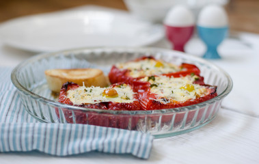 Stuffed red bright pepper with cheese, greens and quail egg in a glass bowl