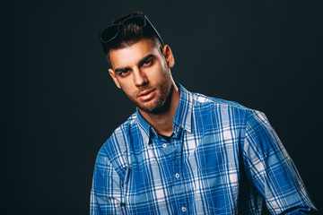 Handsome man with sunglasses posing in studio on dark background