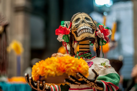 catrina sonriente ene l dia de muertos con trenzas multicolores y una bandeja con flores de cempasuchil dia de muertos mexicanas calaveras halloween