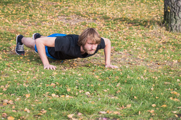 Fototapeta premium Athletic hipster man is doing push-ups in the park.