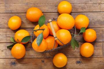 fresh orange fruits in a basket on wooden table, top view
