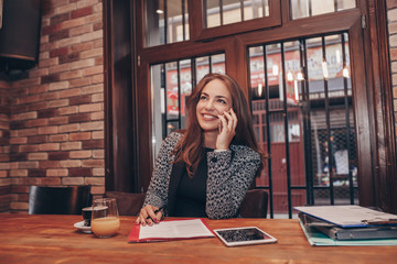 Businesswoman calling on mobile phone and taking notes