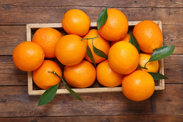 fresh orange fruits in a box on wooden table, top view