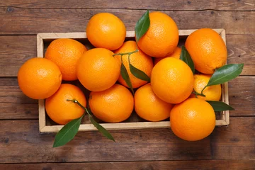 Rolgordijnen Eetkamer vers oranje fruit in een doos op houten tafel, bovenaanzicht