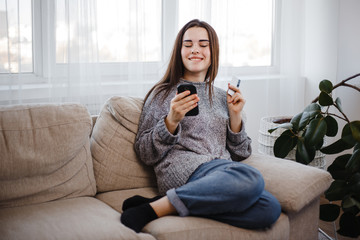 Happy woman shopping at online store with credit card and phone at home. Technology, electronic business