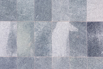 The wall is lined with gray slabs, imitation marble. The texture of the stone panels.
