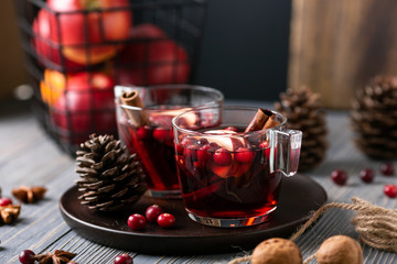 Mulled wine in glasses on a wooden background. Apples, cranberries, cinnamon, star anise, walnuts, cones