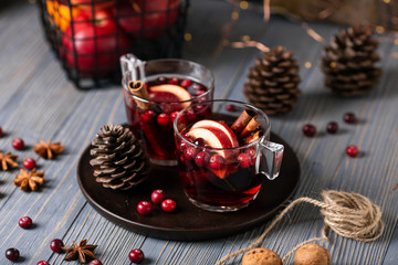 Mulled wine in glasses on a wooden background. Apples, cranberries, cinnamon, star anise, walnuts, cones