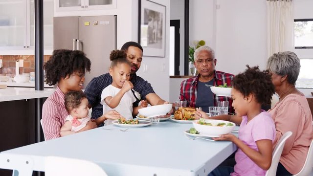 Multi Generation Family Enjoying Meal Around Table At Home