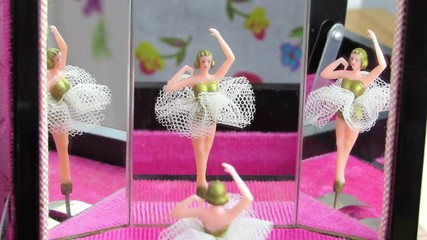 Jewellery box dancing ballerina reflected in three mirrors. The vintage music box ballet dancer pirouettes on a pink base. HD Video.