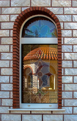 Window of the Orthodox Church of St. George with a dome reflected in it, near Asprovalta, Greece.