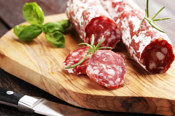 thinly sliced salami on a wooden texture on the background.