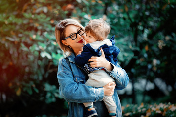 Fototapeta premium Young mother with a baby boy have a fun in a park. Autumn season time