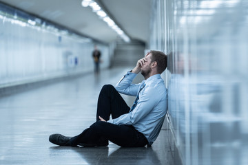 Young businessman crying abandoned lost in depression sitting on ground subway