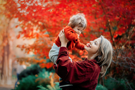 Young mother with a baby boy have a fun in a park. Autumn season time