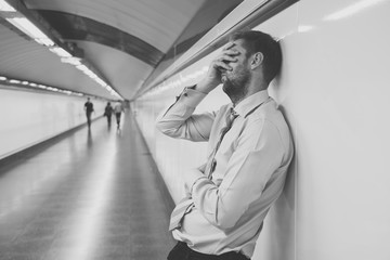 Sad young businessman jobless suffering from depression sitting depressed on ground street subway