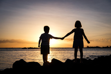 Fototapeta premium Siblings holding hands at sunset