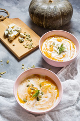 Thick pumpkin soup with feta cheese on concrete background