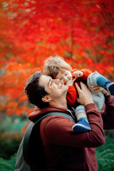 Young father with a child have a fun in a park. Autumn season time