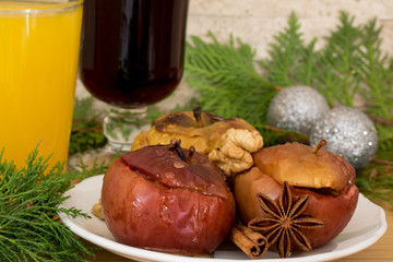 Red mulled wine, sea-buckthorn tea and baked apples with melting honey, nuts and spices, cinnamon and anise. Decorated with fir branches and christmas silver balls, brick wall background.
