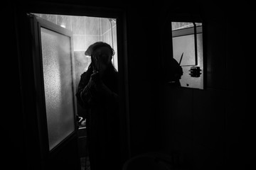 Horror silhouette of woman in window. Scary halloween concept Blurred silhouette of witch in bathroom. Selective focus