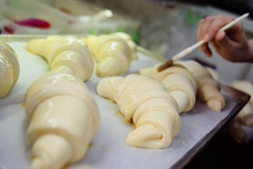 Baker Butters raw croissants in close-up before baking in the oven