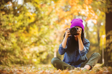Portrait of a young girl in hat with professional camera on fall season park