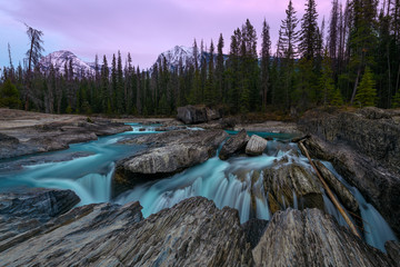 Fototapeta na wymiar Pink sunset over the natural bridge and sinkhole rock formation over Kicking Horse River in Yoho National Park, British Columbia, Canada