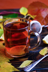 Autumn leaf with raindrops on the table and delicious tea