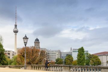 Man standing and talking on the phone at the bridge cross Spree river with background of Berlin...