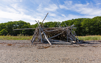 Fototapeta na wymiar Driftwood sticks arranged in a haphazard lean to on a beach in Maine.