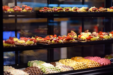 Belgian and Liege waffles with chocolate, berries, sweet sauce, cream in the window of a cafe or store