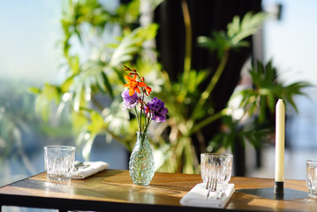 Table in a cafe or restaurant with flowers in a vase and a candle.