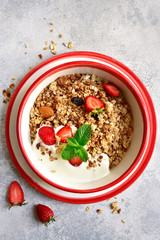 Homemade multicereal organic granola served with fresh strawberry, nuts, honey and yogurt .Top view with copy space.