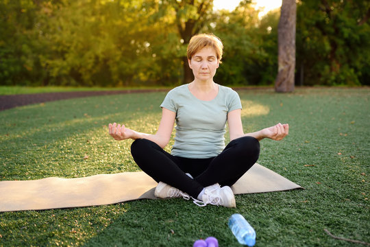 Mature woman practicing yoga outdoor exercise or meditating