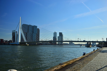 Most wiszący nad rzeką i budynki w słoneczne popołudnie.