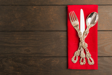 Set of tableware on red tissue over wooden table
