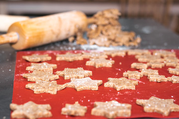 Star shaped cinnamon christmas cookies with dough roll in background