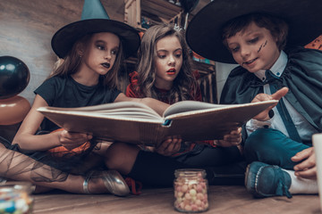 Little Children in Halloween Costumes Reading Book